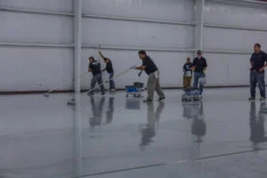 AIF field team laying a sleek, white glossy epoxy floor throughout a warehouse facility
