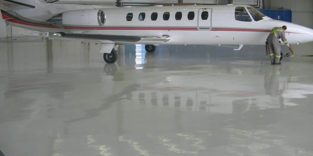 high-gloss, chemical resistant airplane hangar floor with aircraft in the middle