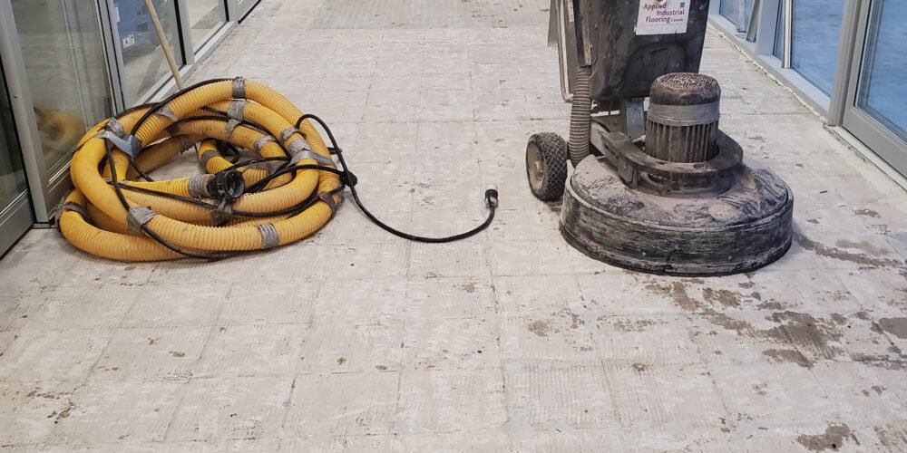 Surface preparation with concrete grinding equipment at Home Hardware store entrance in Ontario before installing MMA industrial high-traffic flooring